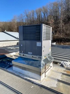 Commercial rooftop HVAC unit installation with metal mounting platform and ductwork