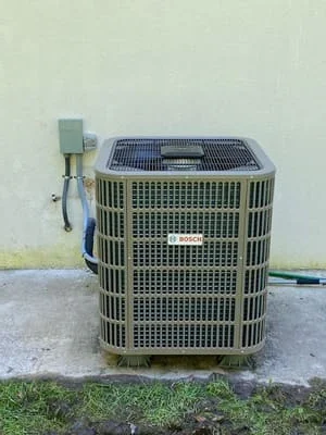 New AC condenser unit installed on concrete pad with electrical disconnect and refrigerant lines