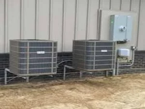 Two commercial AC condensing units and tankless water heater on concrete pad installation