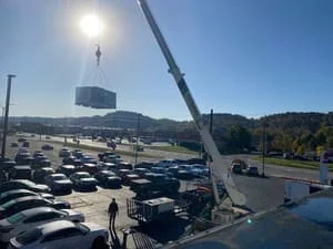 Crane lifting commercial HVAC unit onto rooftop during installation